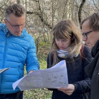 Three people outside looking at a map